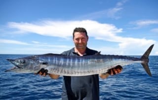 Photo of a Man Holding a Barracuda, Led by One of the Best Port Aransas Fishing Guides.